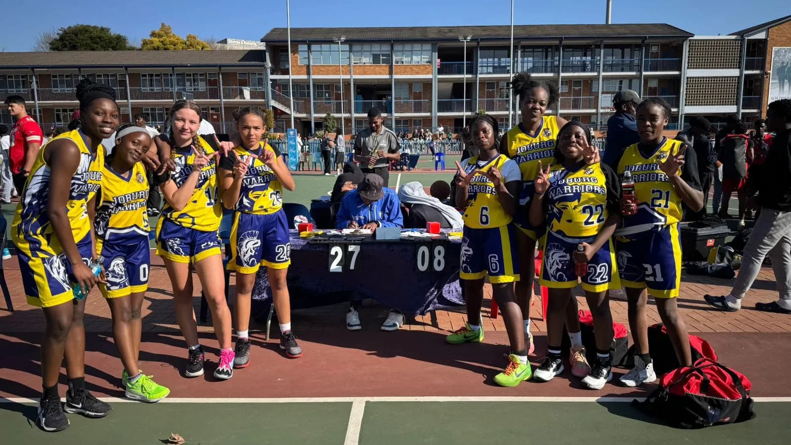 Joburg Warriors girls' squad posing beside the score table at a tournament