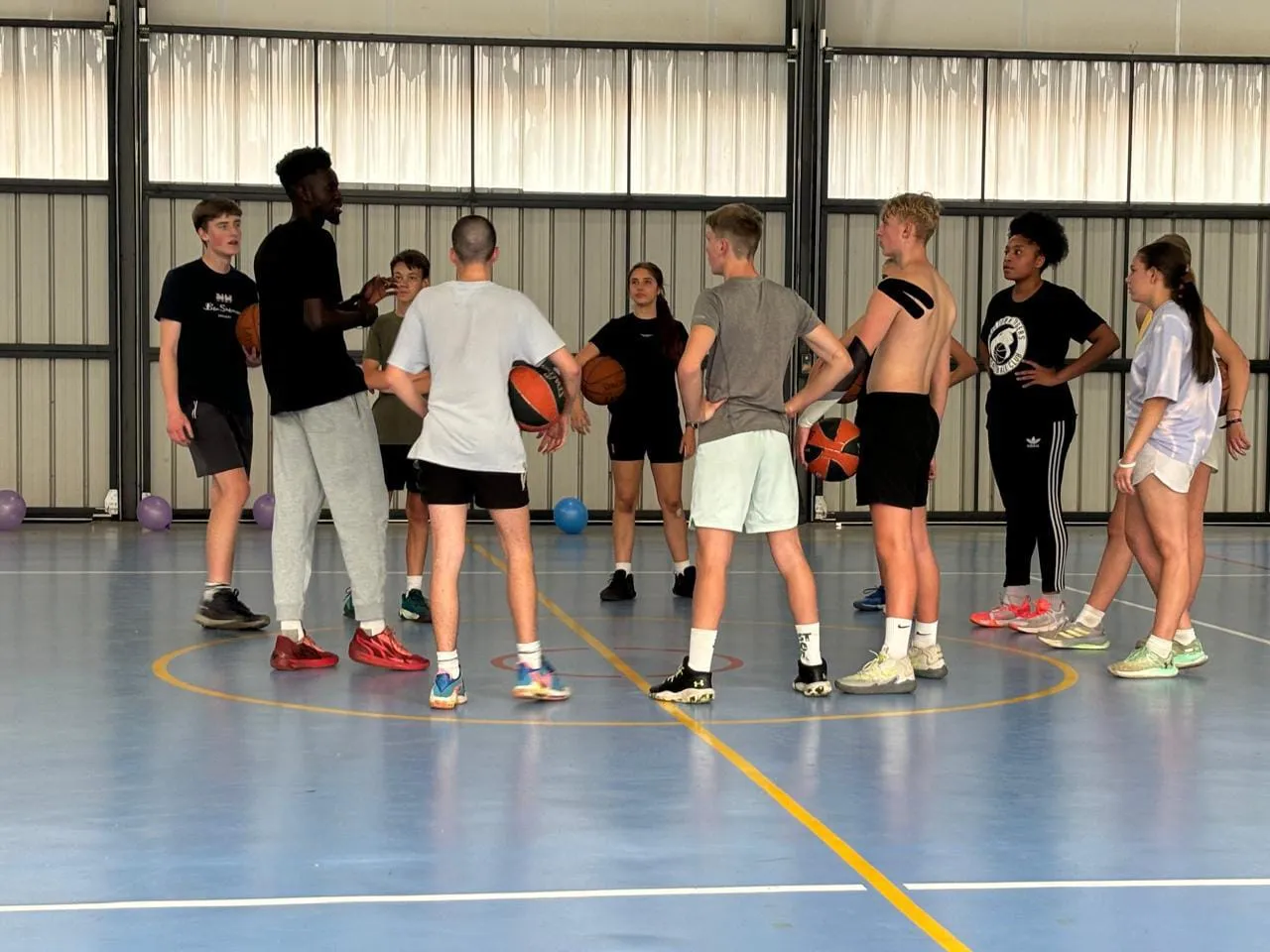 A coach talking a group of players through a drill during an indoor skills session