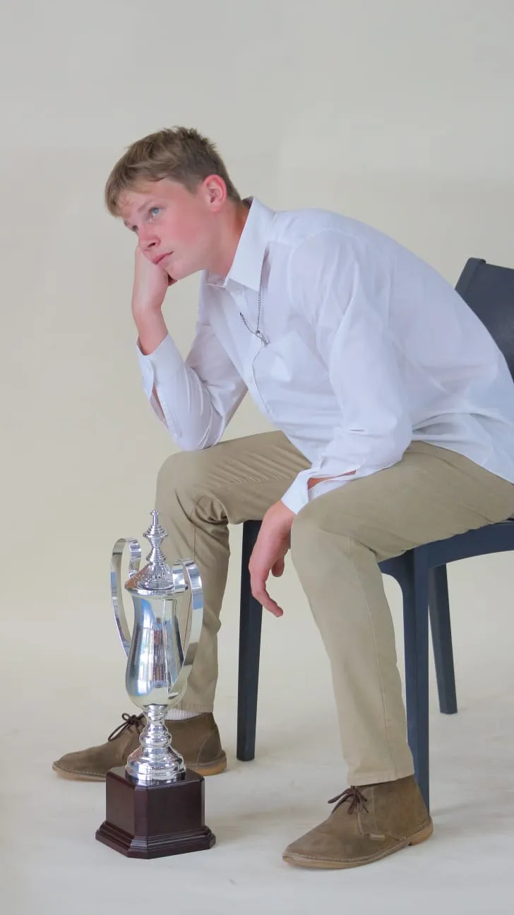 A young Warriors player seated beside a silver trophy